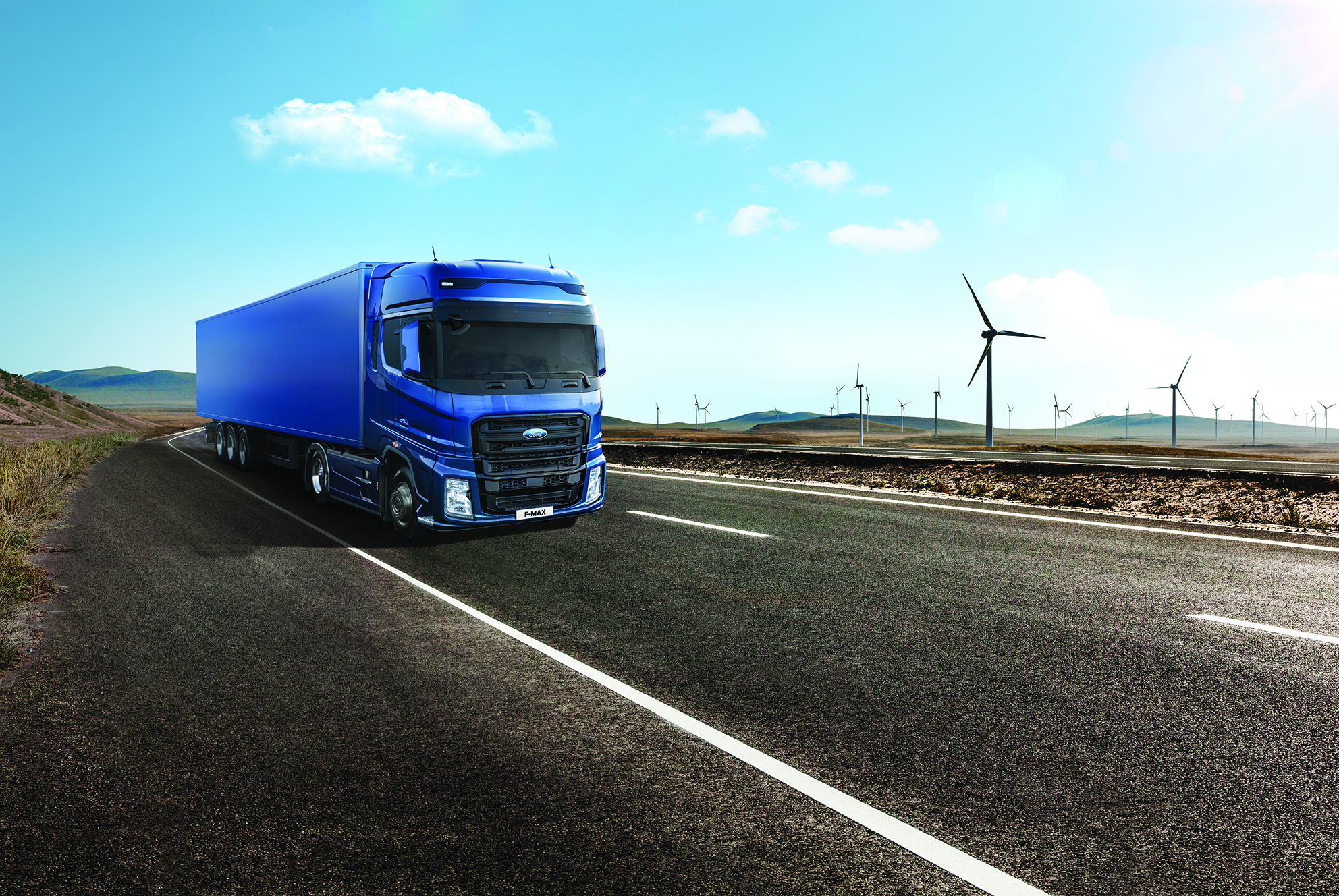 משאית FMAX כחולה כשברקע שבשבות של אנרגיית רוח