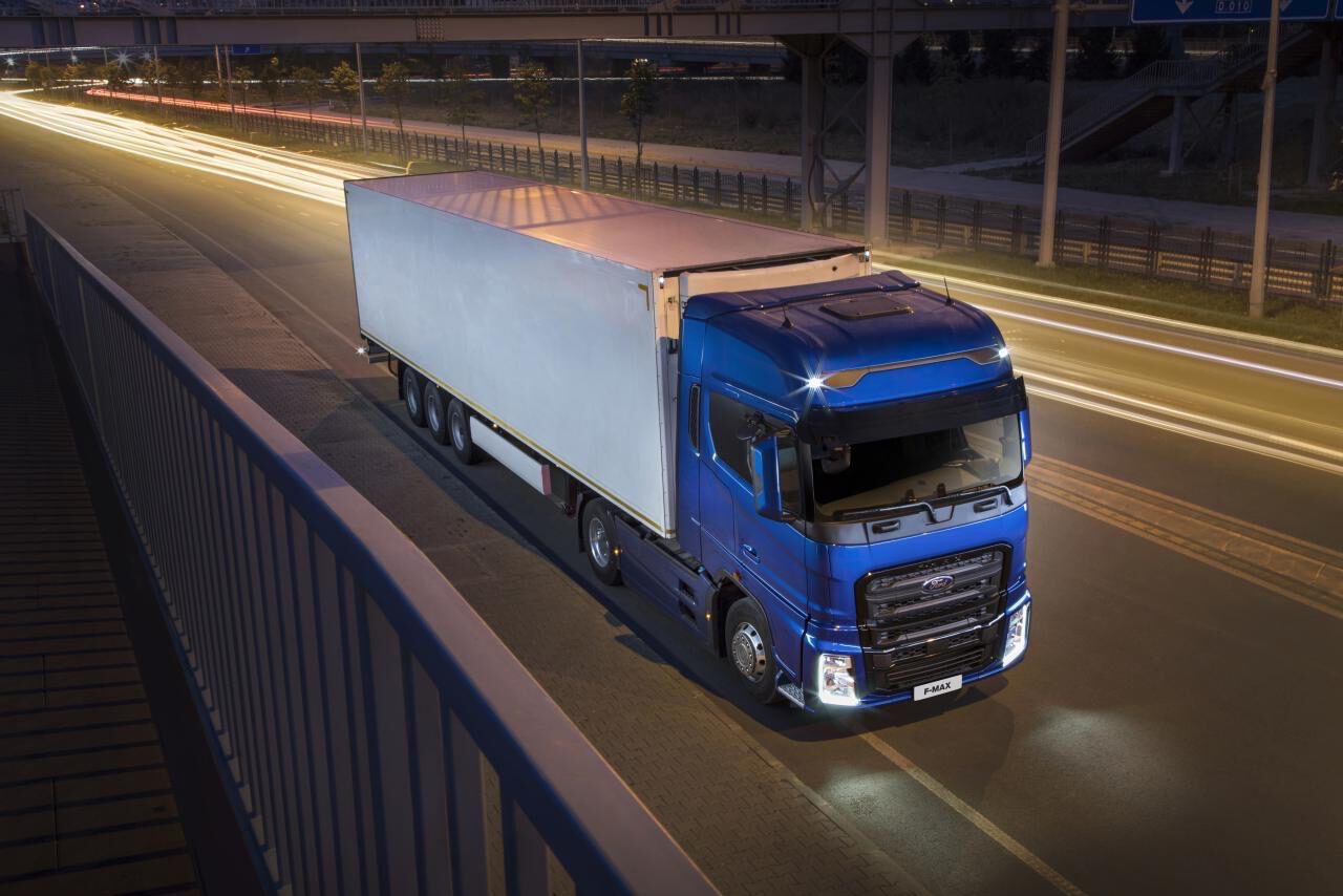 משאית FMAX כחולה בנסיעה לילית עם שובל אורות